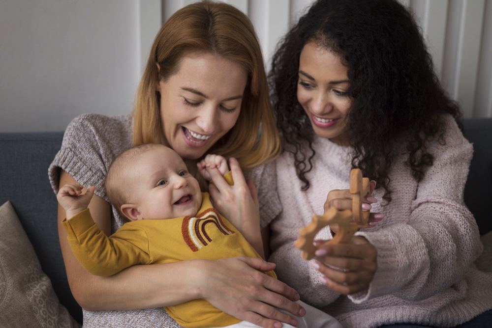 Doula holding a newborn while their mother rests during a daytime visit