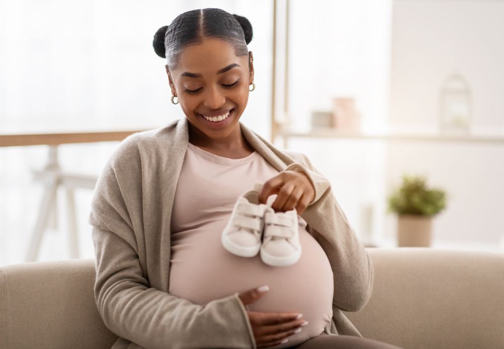 Expectant mother holding a pair of baby shoes while preparing for birth