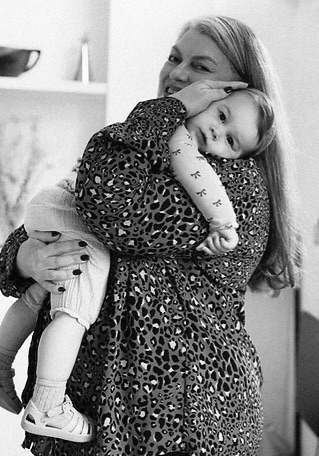 Cameron holding a toddler on her hip at home